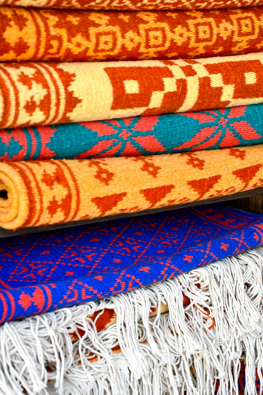 a pile of colorful rugs sitting on top of each other