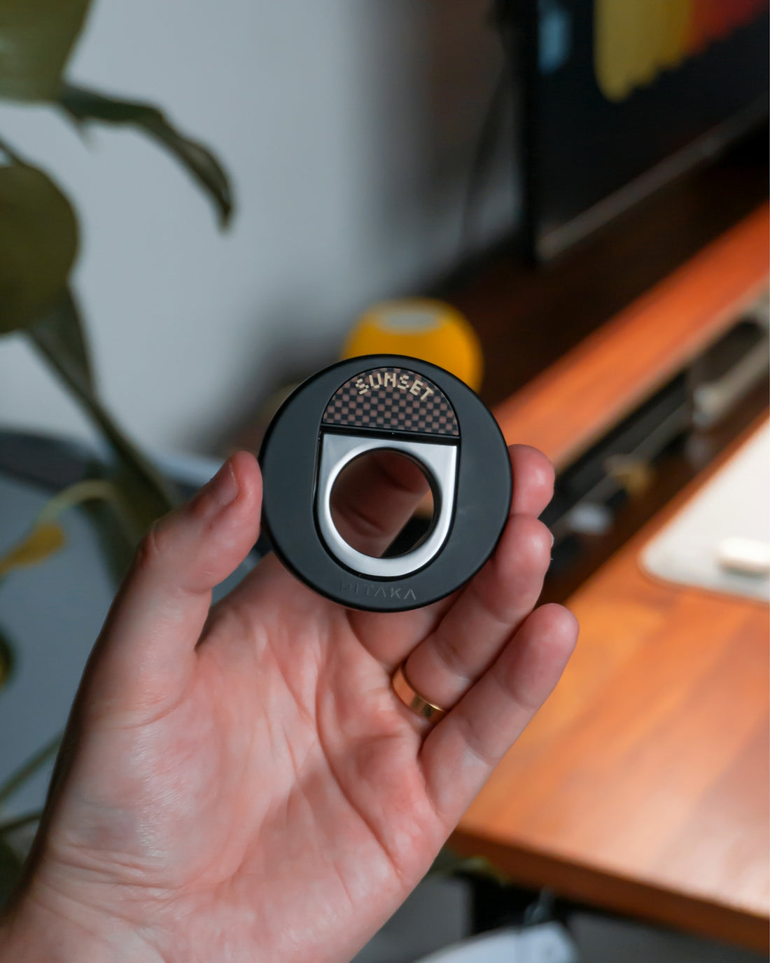 A hand holds a circular object with a square hole.