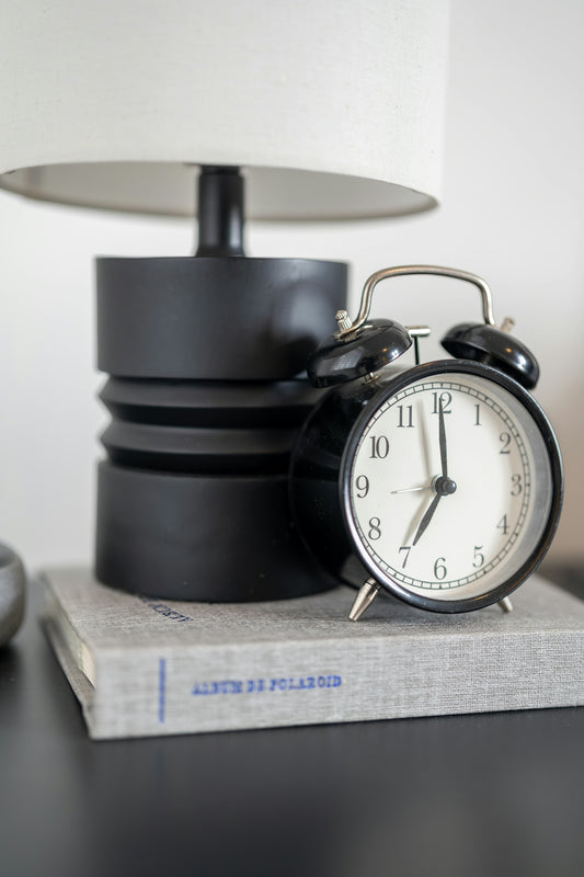 A black alarm clock sits on a book.