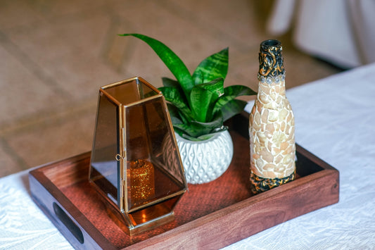 Decorations on a wooden tray with a candle and plant.