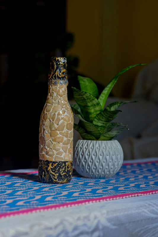 Decorated bottle and potted plant on table
