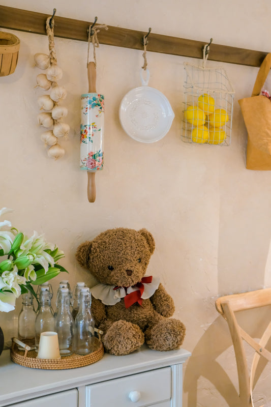 Teddy bear with flowers and kitchen items on shelf